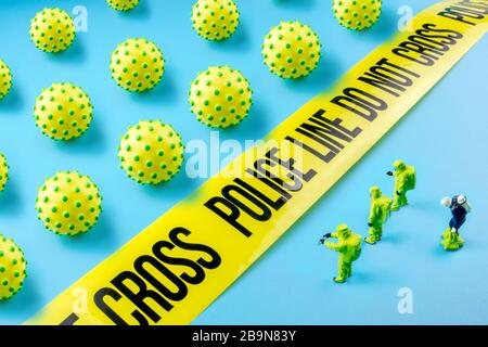 closeup of many little corona viruses waiting in front of do not cross line and special medical biohazard team in protective green suits guarding the Stock Photo