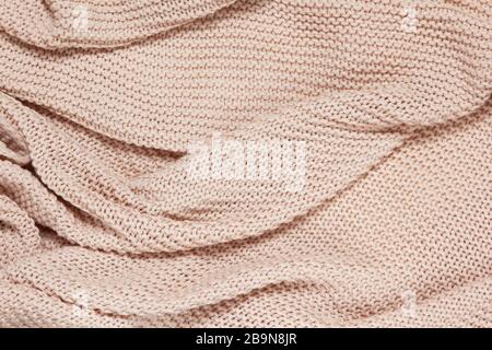 Textured surface of knitted cotton wave plaid, top view. Soft dusty pink pastel wool backdrop. Seasonal cosiness flat lay. Scandinavian minimal style. Stock Photo