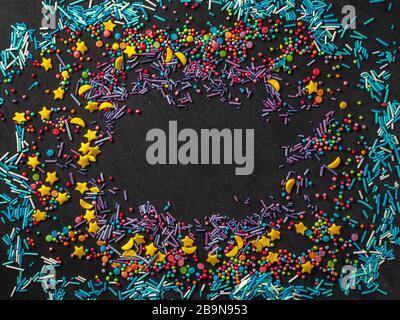 Sprinkles grainy. Confectionery concept. Sweet confetti on a black background. Cupcake, donuts, dessert, bakery background. For making holiday designs, parties, birthday, wedding invitations. Stock Photo