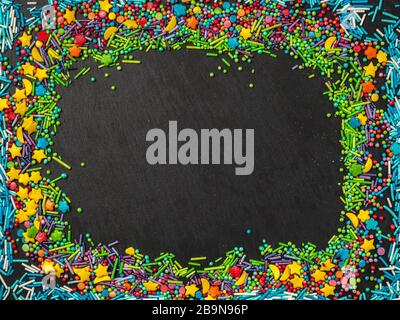 Sprinkles grainy. Confectionery concept. Sweet confetti on a black background. Cupcake, donuts, dessert, bakery background. For making holiday designs, parties, birthday, wedding invitations. Stock Photo