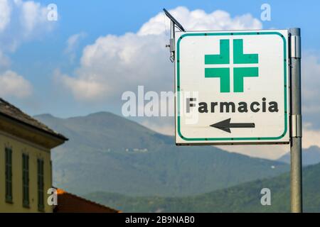 LAKE COMO, ITALY - JUNE 2019: Sign showing the way to a Pharmacy in one a town alongside Lake Como, There is a solar panel on top to power the lights Stock Photo