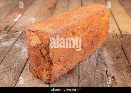 Red brick on a wooden table. Building material from baked clay. Light background. Stock Photo