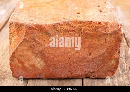 Red brick on a wooden table. Building material from baked clay. Light background. Stock Photo