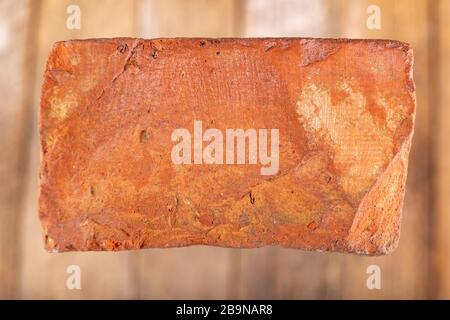Red brick on a wooden table. Building material from baked clay. Light background. Stock Photo