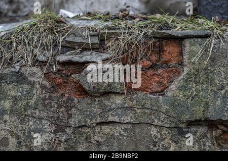 Old wall from a red brick shattered cracked plaster. Abstract background. Stock Photo