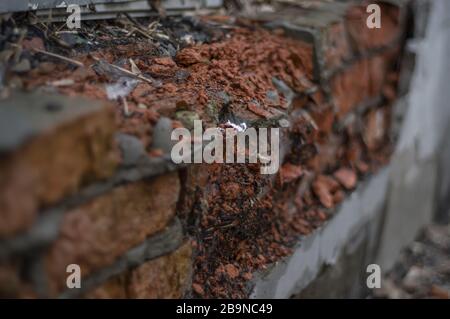 Old brick wall made of red-orange brick. Shattered surface. An abandoned house or an old factory Stock Photo