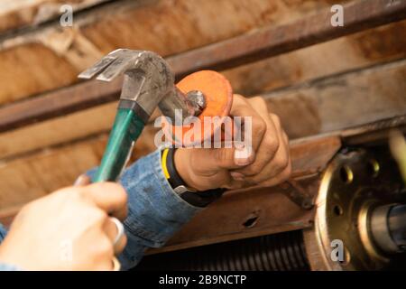 Human hand making holes using hole rolling gate puncher by hammer. Stock Photo