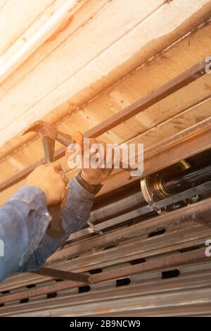 Human hand making holes using hole rolling gate puncher by hammer. Stock Photo