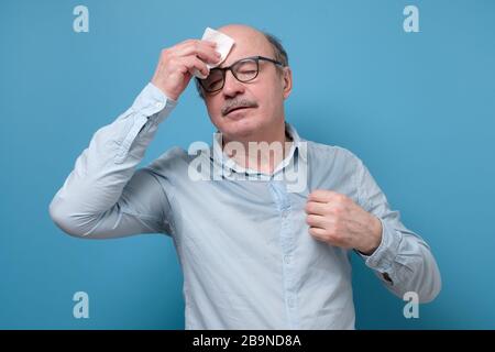 Senior employee sweating in a warm office wiping a forehead Stock Photo