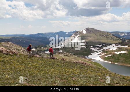 Two unidentifiable tourists hike across a beautiful landscape leading to Gardner Lake in the Shoshone National Forest, Wyoming. Stock Photo