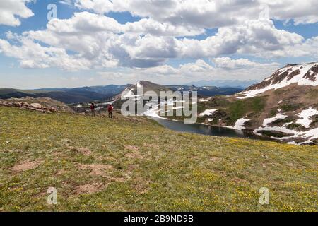 Two unidentifiable tourists hike across a beautiful landscape leading to Gardner Lake in the Shoshone National Forest, Wyoming. Stock Photo