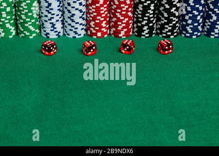 Large copy writing space with betting chips and 4 translucent red casino style dice on a green felt playing surface.  Vivid colors and contrast on the Stock Photo