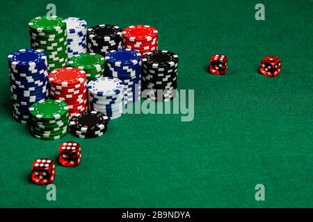 Large copy writing space with betting chips and 4 translucent red casino style dice on a green felt playing surface.  Vivid colors and contrast on the Stock Photo