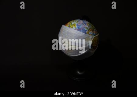 Globe in a surgical mask, safety mask, concept of global pandemic or epidemic on black background Stock Photo