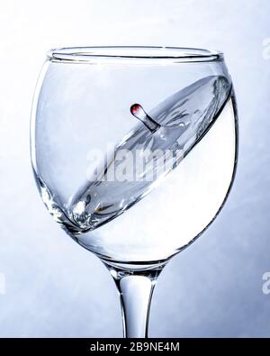 a splash of water in a glass, a falling drop. Light background. Stock Photo