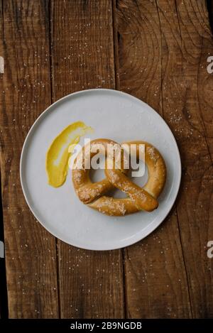 salted soft pretzel and mustard smear on white plate Stock Photo