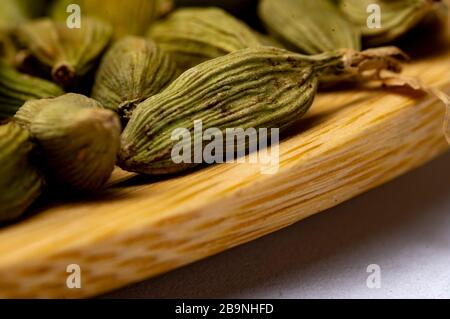 green cardamom on wooden spoon. white background. Close-up photo. Stock Photo