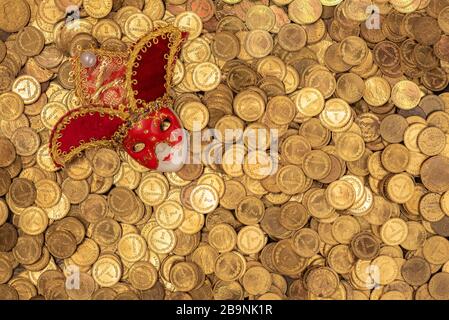 Pile of small golden coins with Venetian mask Stock Photo