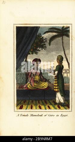 A female Mamelouk of Cairo in Egypt, 1818. Mamluk woman in turban seated on a cushion on a terrace being served tea by a servant. Handcoloured copperplate engraving from Mary Anne Venning’s A Geographical Present being Descriptions of the Principal Countries of the World, Darton, Harvey and Darton, London, 1818. Venning wrote educational books on geography, conchology and mineralogy in the early 19th century. Stock Photo
