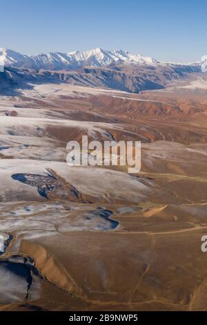 aerial landscape showing badland in the Tian Shan mountains arounf the amazing Ozero Torpo, a lake surrounded by eroded mud hills along the Mels-Ashu Stock Photo