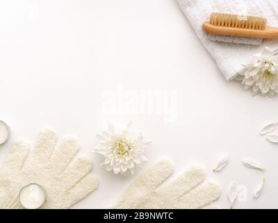 Spa Kit. Wooden brushes limestone stone heel, scrub gloves, towels, peonies flowers and petals on white color background. Aromatherapy massage depilat Stock Photo