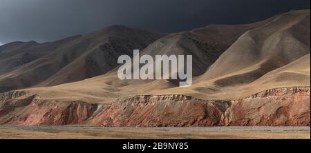 Bad weather bringing the first autumn snow over the colorful red rocks of the Arpa valley along the Arpa and Jamanti river in the Tian Shan mountains Stock Photo