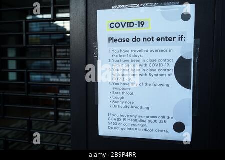 Please do not enter shop if you are suffering from symptoms for coronavirus covid-19 in a shop window in St Heliers, Auckland, New Zealand. Stock Photo