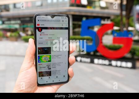 Using smartphone in front of 5G sign Stock Photo