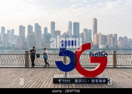 People using smartphone near a 5G sign Stock Photo