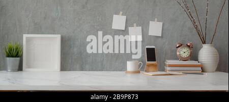 Cropped shot of comfortable workspace with smartphone, books, decorations and copy space on white table with loft wall Stock Photo