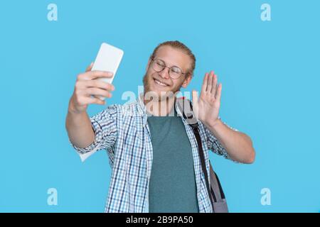 Handsome young man making selfie waving hand. Stock Photo