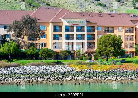 Courtyard Marriott hotel exterior view at scenic Oyster Point waterfront and green slopes of San Bruno Mountain ridge - South San Francisco, CA, USA - Stock Photo