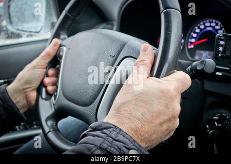 Men's hands on the steering wheel of a car. The driver controls the car. Stock Photo
