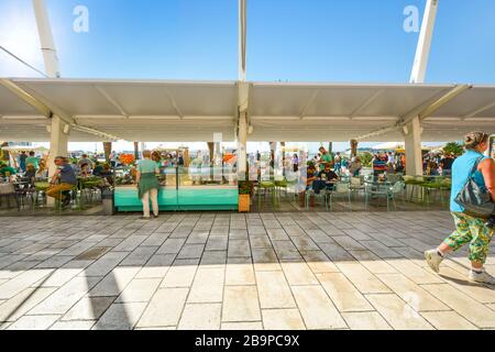 Tourists enjoy a cafe on a sunny day at Riva Promenade along the harbor of the Adriatic sea on the Dalmation Coast of Split, Croatia Stock Photo