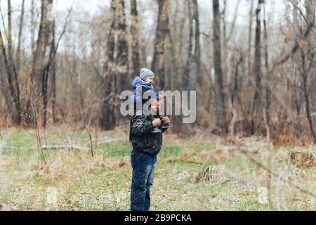 Happy weekend concept. happy grandfather and grandson are walking in forest. Spring. Grandpa rolls on the shoulders of a little boy Stock Photo