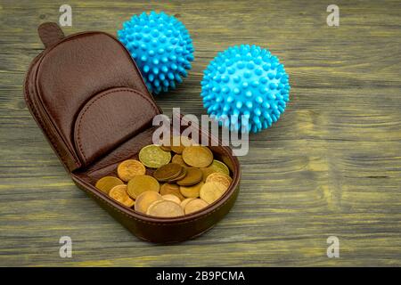 High-angle view of an open brown leather wallet full of golden coins next two blue virus molecules as concept for the covid-19 pandemy and the financi Stock Photo
