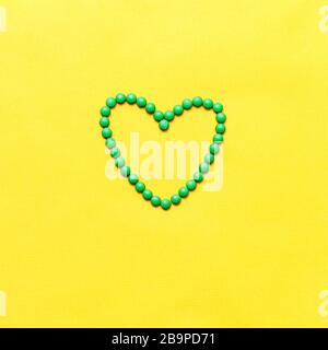 green round pills tablets heart shape on yuellow background Stock Photo