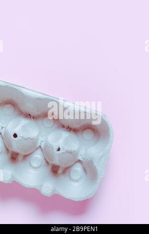 Empty box for eggs on a neon light on a pink background. Product shortage concept. Stock Photo