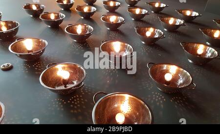 Round lamps made from colanders with shining glass bulbs inside. Abstract geometric patterned background. Light dots from light bulb on grey backdrop. Stock Photo