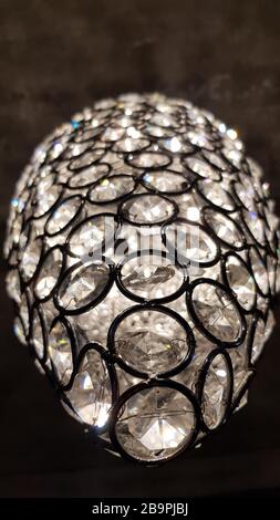 Circle black wire scales with crystal elements inside. Shiny surface of unusual glass chandelier. Modern sparkling round glass lampshade texture. Stock Photo