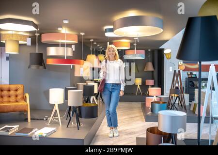 Woman with a bag on shoulder standing in the lamps section. Stock Photo