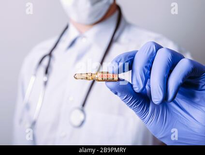 Conceptual image of medical doctor holding dose with COVID-19 vaccine cure. Stock Photo