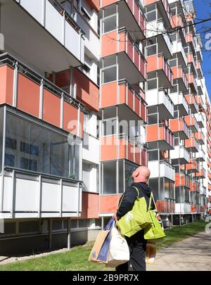 24 March 2020, Saxony, Leipzig: Jürgen Burscher from the 'Alter, Leben und Gesundheit' association is returning to one of the longest apartment blocks in Germany, the 'Lange Lene', with the purchases ordered by senior citizens who are no longer expected to leave their homes. Using face masks and protective gloves, more than 200 elderly people are cared for by the association's staff in the 335-meter-long prefabricated concrete slab building of the Leipziger Wohnungsbaugesellschaft (LWB), also as a small family substitute. In order to ensure that lunch is safe because the cafeteria is now close Stock Photo