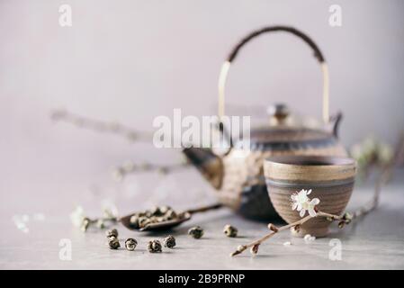 Traditional asian tea ceremony arrangement. Flat lay of iron teapot, cups and blooming cherry tree flowers on grey concrete background. Spring concept Stock Photo