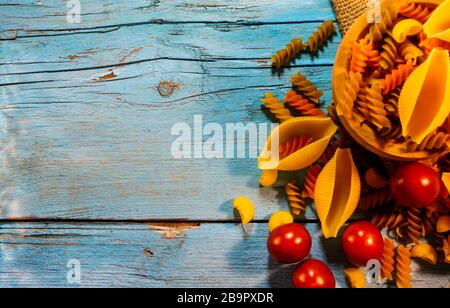 Flat lay composition with different pasta and tomatoes on color background, space for text. Dry uncooked whole pasta Stock Photo