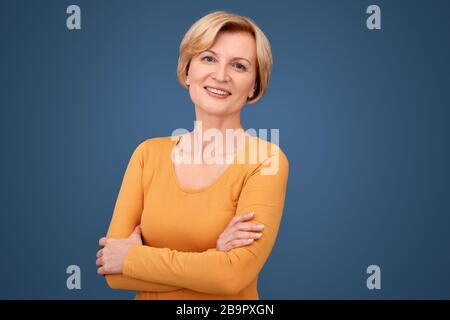 Middle aged woman crossed hand on chest, smiling wide Stock Photo