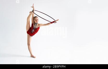 Young girl in bright sports clothes performing exercise with hoop on white background, blank space Stock Photo