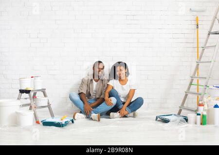 Husband and wife with tools for repair on white brick wall background Stock Photo