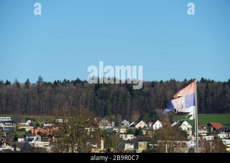 Damaged or ragged Serbian flag, waving in the blowing wind in allotment garden colony Urdorf, Switzerland Stock Photo