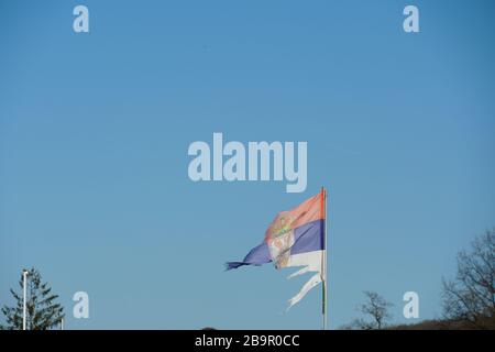 Damaged or ragged Serbian flag, waving in the blowing wind. Stock Photo